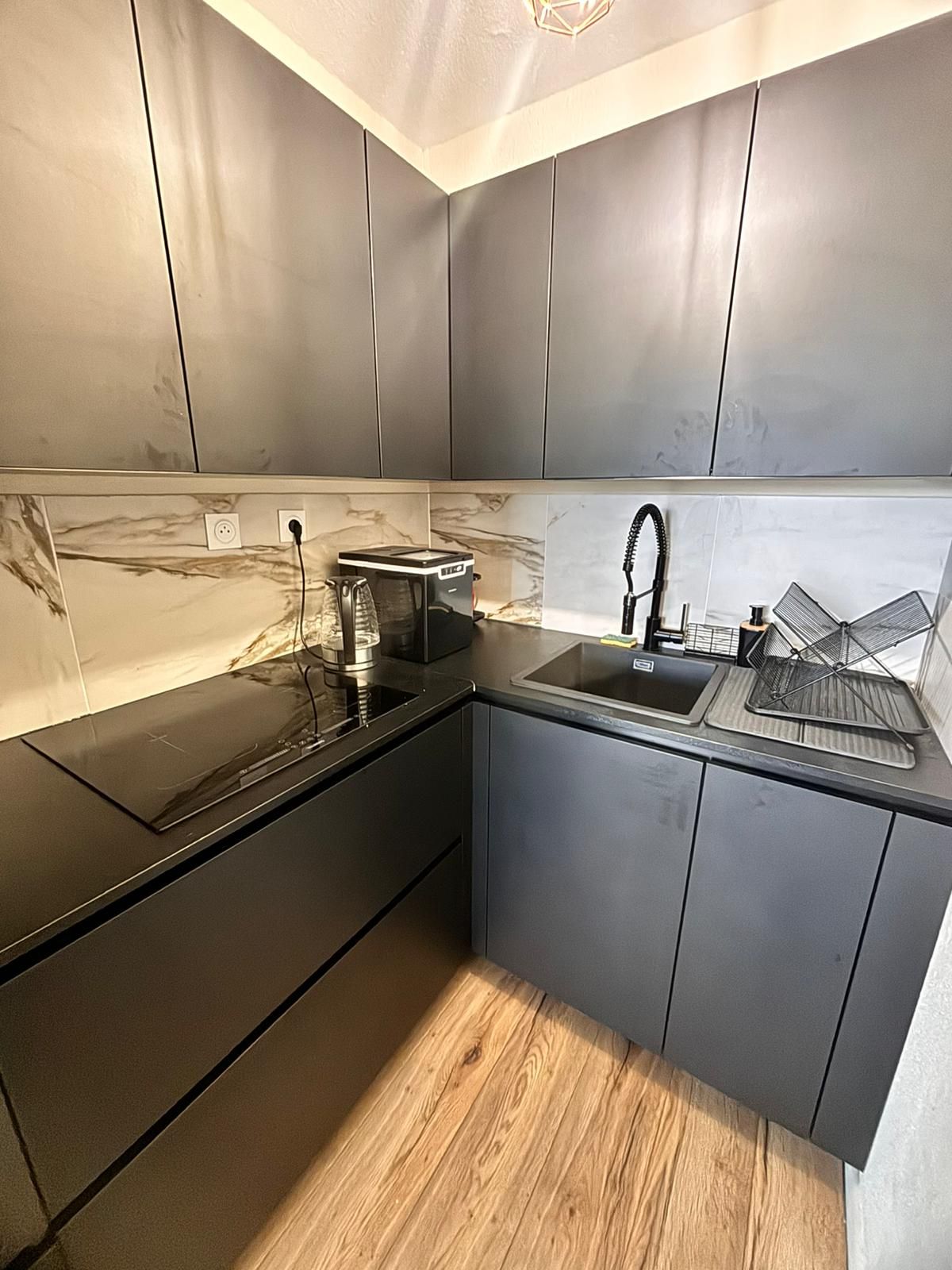 A modern kitchen with a black countertop, a built-in oven, and a sink.