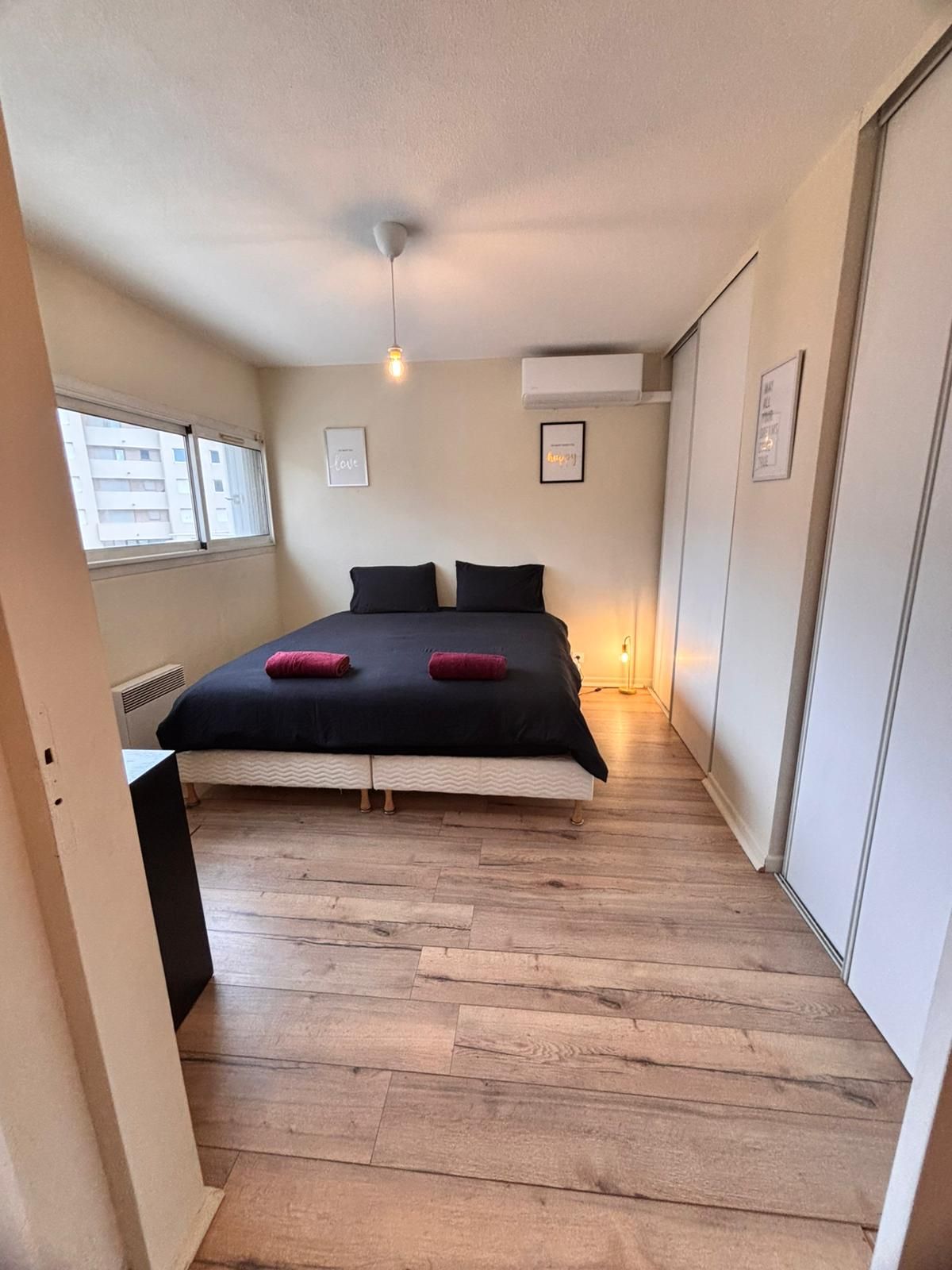 Une chambre à coucher avec un lit, une fenêtre et un climatiseur fixé au mur.