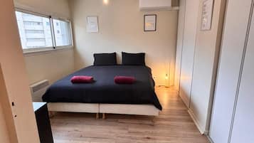 Une chambre à coucher avec un lit, une fenêtre et un climatiseur fixé au mur.