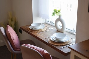 A dining table with white plates and bowls, a glass, and a vase with flowers. - Cosy One-Bedroom Flat in Southsea (Portsmouth)