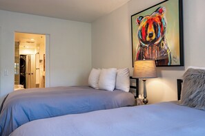 Ett hotellrum med två sängar, en tavla på väggen och ett badrum som syns genom en öppen dörr.