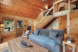 A wooden interior with a sofa, a chair, a staircase, and a window. - Creekside Haven - Fightingtown Creek Cabin in Cherry Log (Cherry Log)