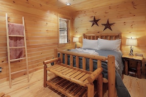 A wooden cabin room with a bed, a bench, a ladder, and two star decorations on the wall. - Creekside Haven - Fightingtown Creek Cabin in Cherry Log (Cherry Log)