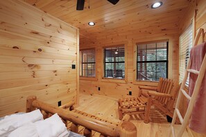 A wooden cabin interior with a bed, a bench, and a sauna area. - Creekside Haven - Fightingtown Creek Cabin in Cherry Log (Cherry Log)