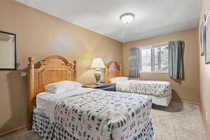 A hotel room with two beds, a nightstand, a lamp, and a window with curtains. - Gorgeous 3 bedroom on Eagle River chain of lakes with indoor pool and jacuzzi (Eagle River)