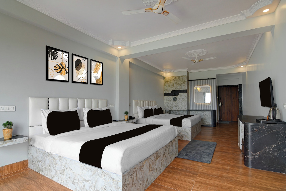 A modern hotel room with a large bed, a desk, and a seating area.
