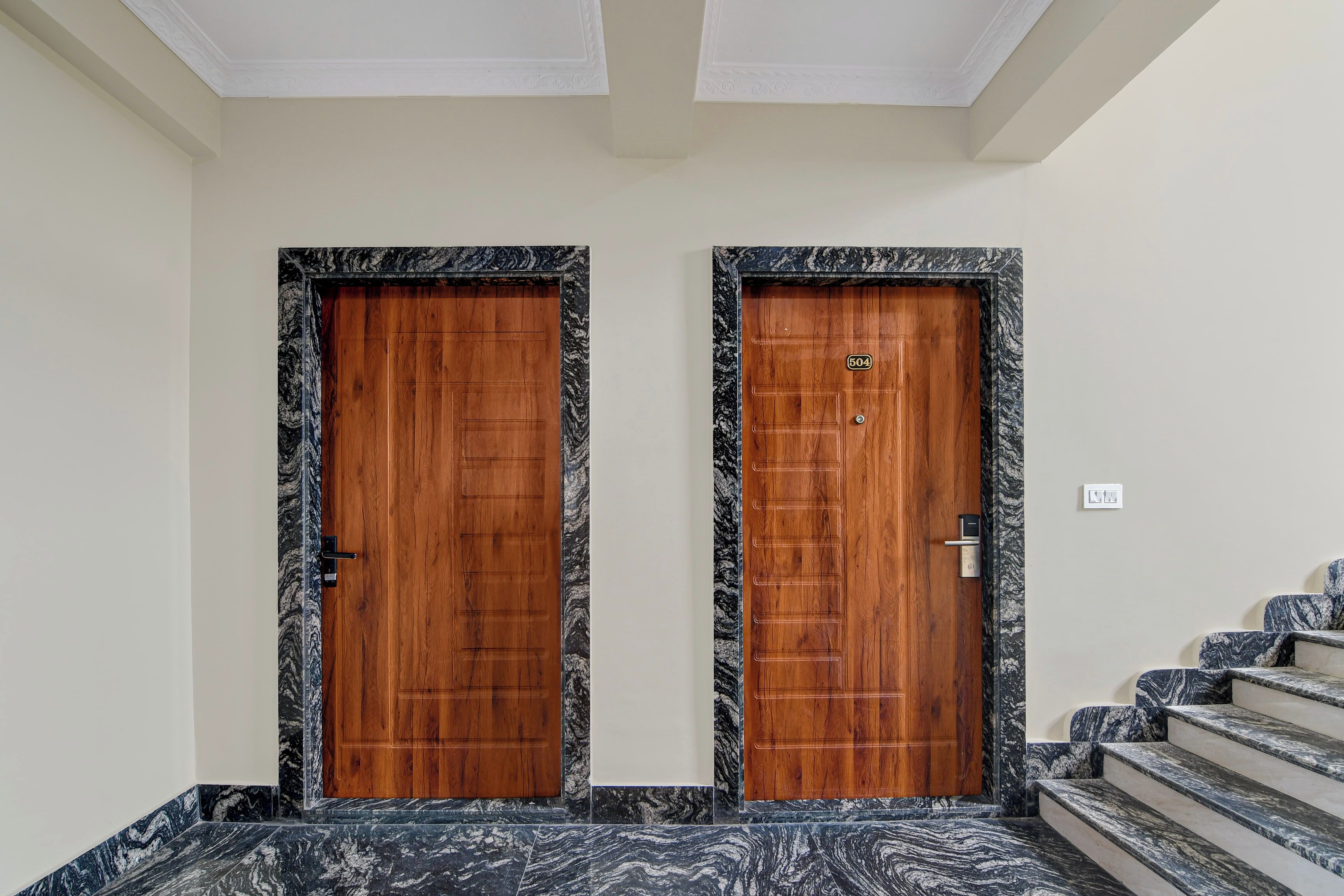 Two wooden doors with a marble frame, a staircase with marble steps, and a ceiling with a decorative pattern.