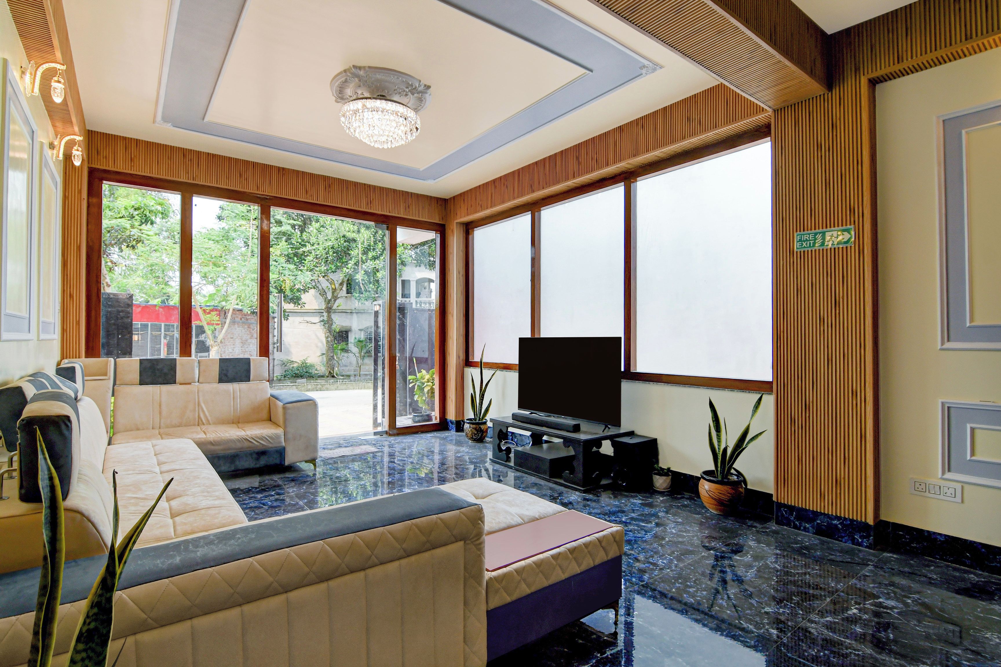 Una sala moderna con un sofá modular, un televisor de pantalla plana y ventanas amplias.