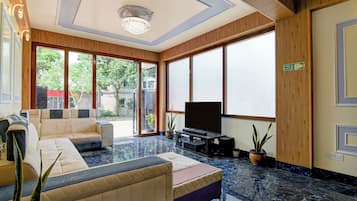 Una sala moderna con un sofá modular, un televisor de pantalla plana y ventanas amplias.
