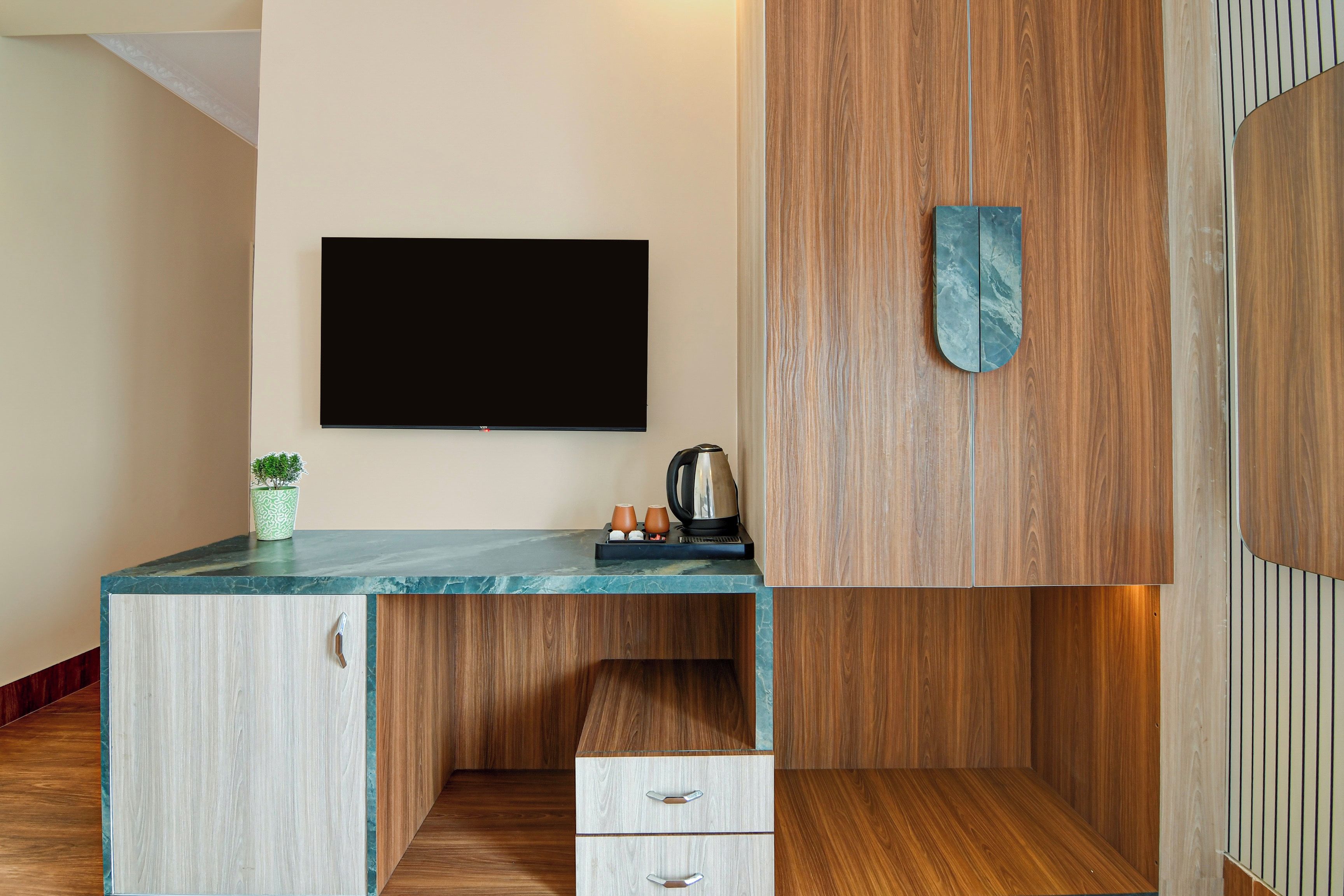 Una cocina moderna con televisión integrada, armarios de madera y encimera de mármol.