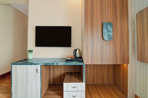 A modern kitchen with a built-in TV, wooden cabinets, and a marble countertop. - Palette Hotel and Resort Mayapur (Krishnanagar)