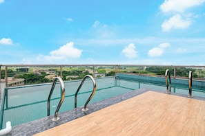 A rooftop infinity pool with a wooden deck and metal railings, overlooking a residential area. - Palette Hotel and Resort Mayapur (Mayapur)