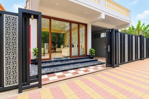 A modern building with a glass entrance, a checkered floor, and a decorative metal gate.