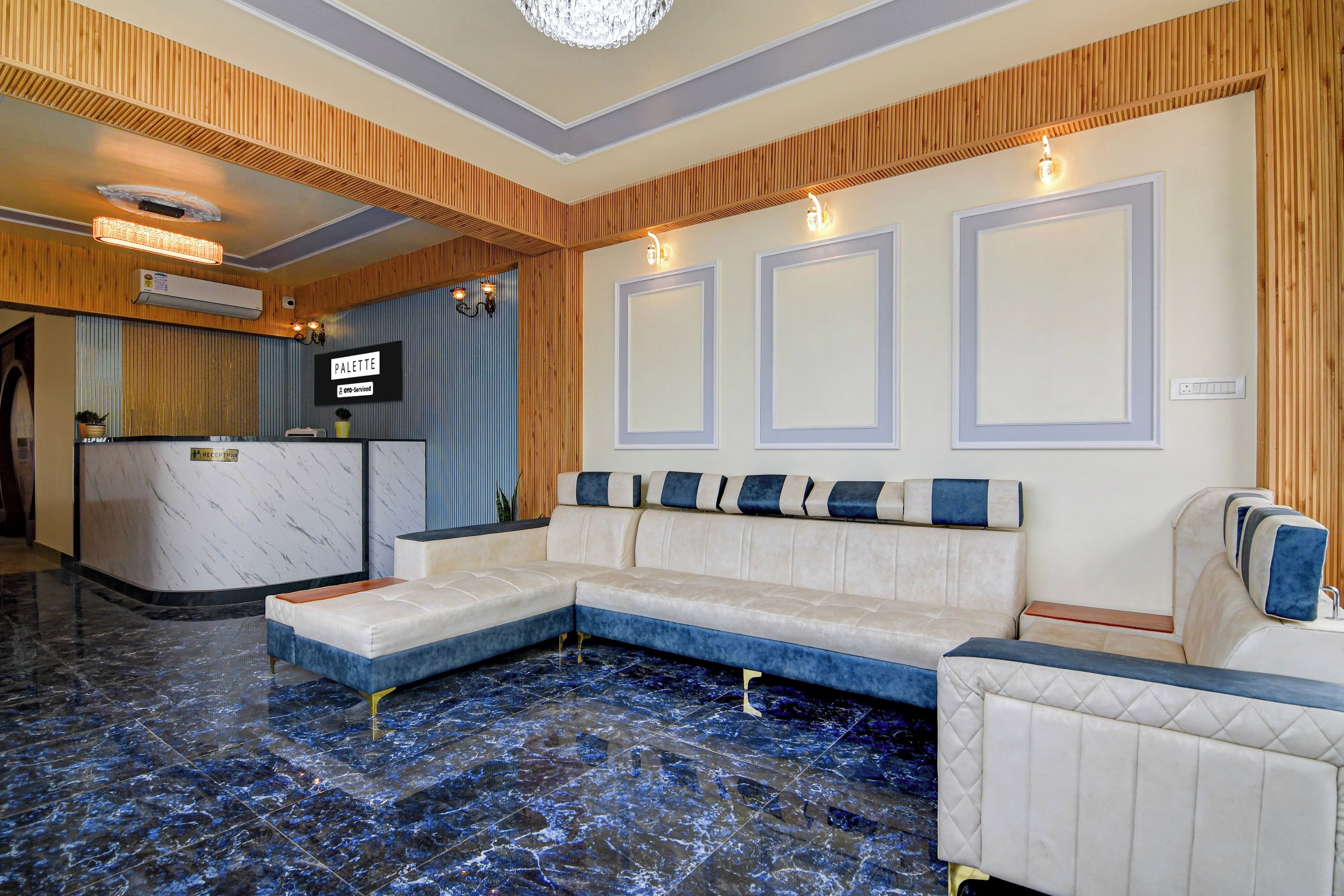 En hotellobby med en receptionsdisk, en sittgrupp med en soffa och fåtöljer samt ett marmorgolv.