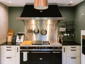 A kitchen with a stove, pots, and a coffee maker. - Architect-designed villa in the heart of the Luberon, blending nature, design, and the art of living (Robion)