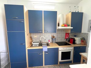 A compact kitchen with blue cabinets, a microwave, an oven, and a sink. - Country House 'Iron Hill Villa' with Sea View, Wi-Fi and Air Conditioning (Κρανίδι)