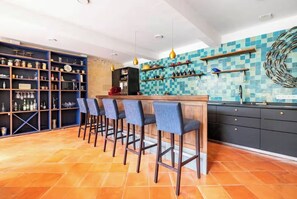 A kitchen with a bar area, shelves with kitchenware, and a tiled backsplash. - Italian-style villa by the river, near Bordeaux (Quinsac)