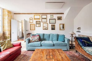 A living room with a light blue sofa, a red sofa, a wooden coffee table, and a variety of framed pictures on the wall. - Italian-style villa by the river, near Bordeaux (Quinsac)