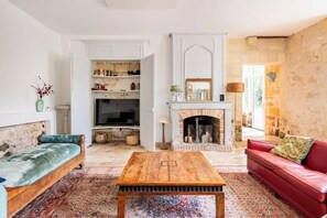 A living room with a fireplace, a television, a red sofa, and a wooden coffee table. - Italian-style villa by the river, near Bordeaux (Quinsac)