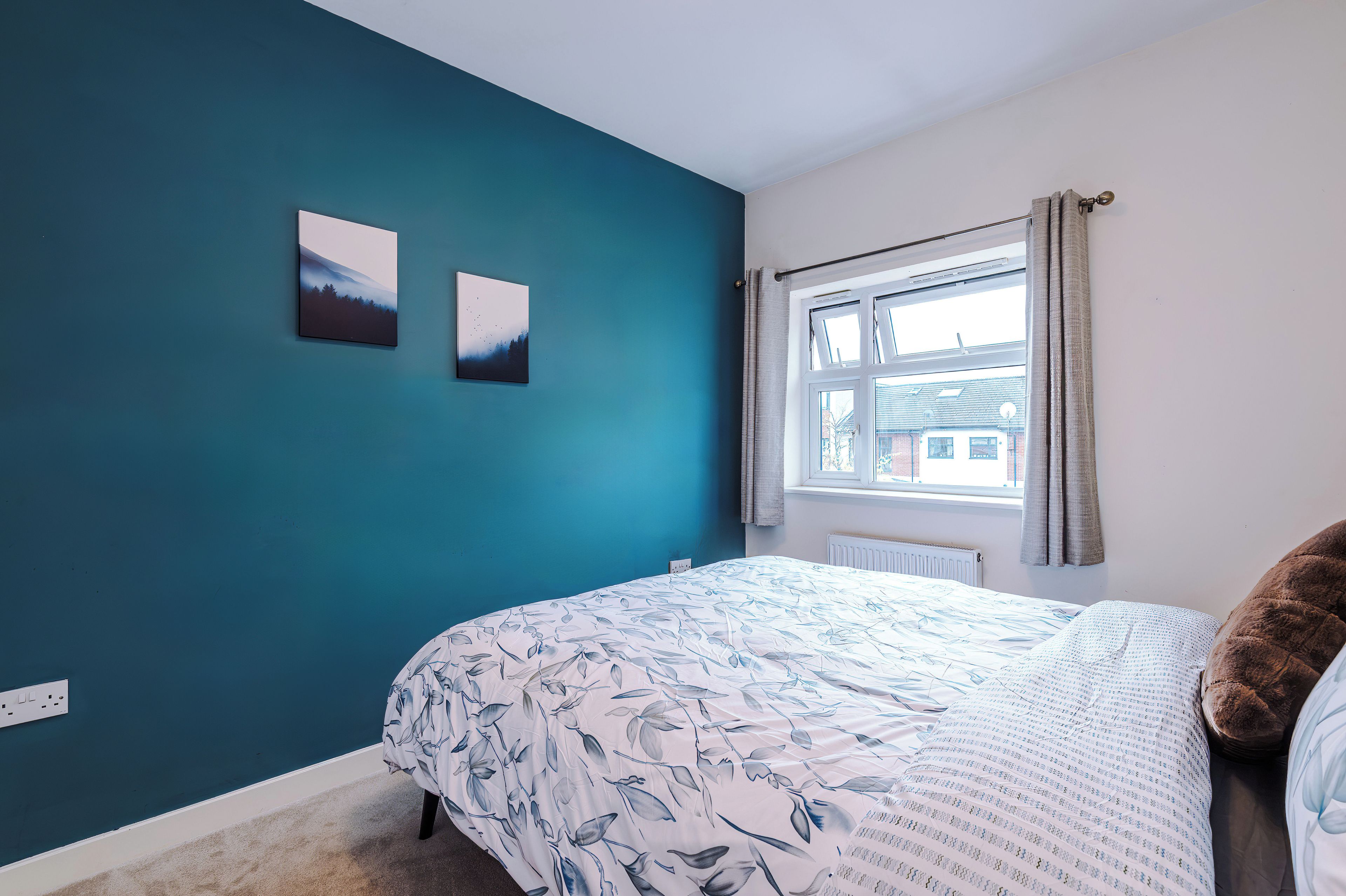 Une chambre à coucher avec un lit, une fenêtre et deux tableaux accrochés au mur.