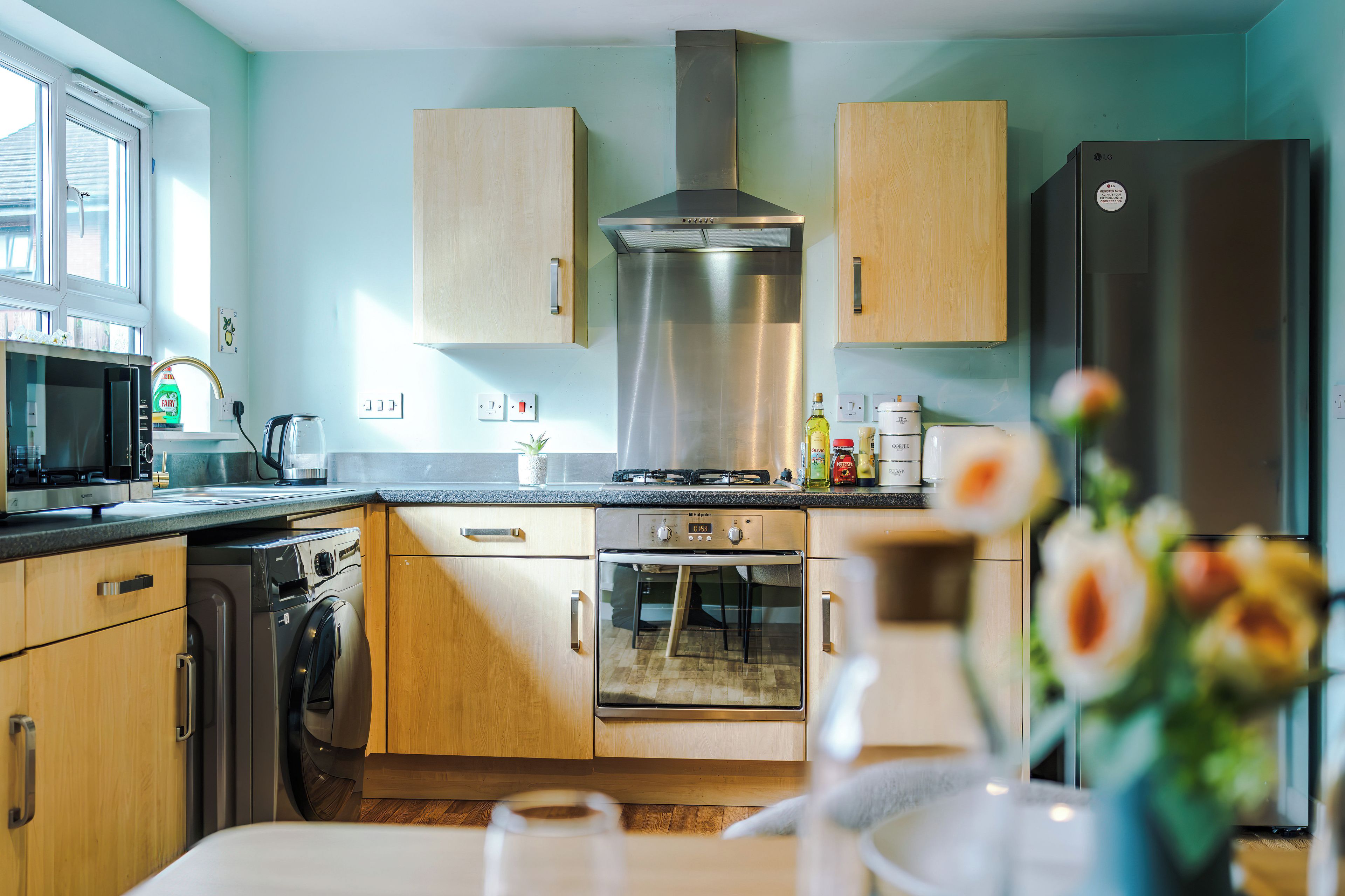 Une cuisine moderne dotée d’appareils électroménagers en acier inoxydable, de meubles en bois et d’une grande fenêtre.