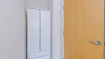 Une armoire blanche avec deux tiroirs et une porte en bois dotée d’une poignée.