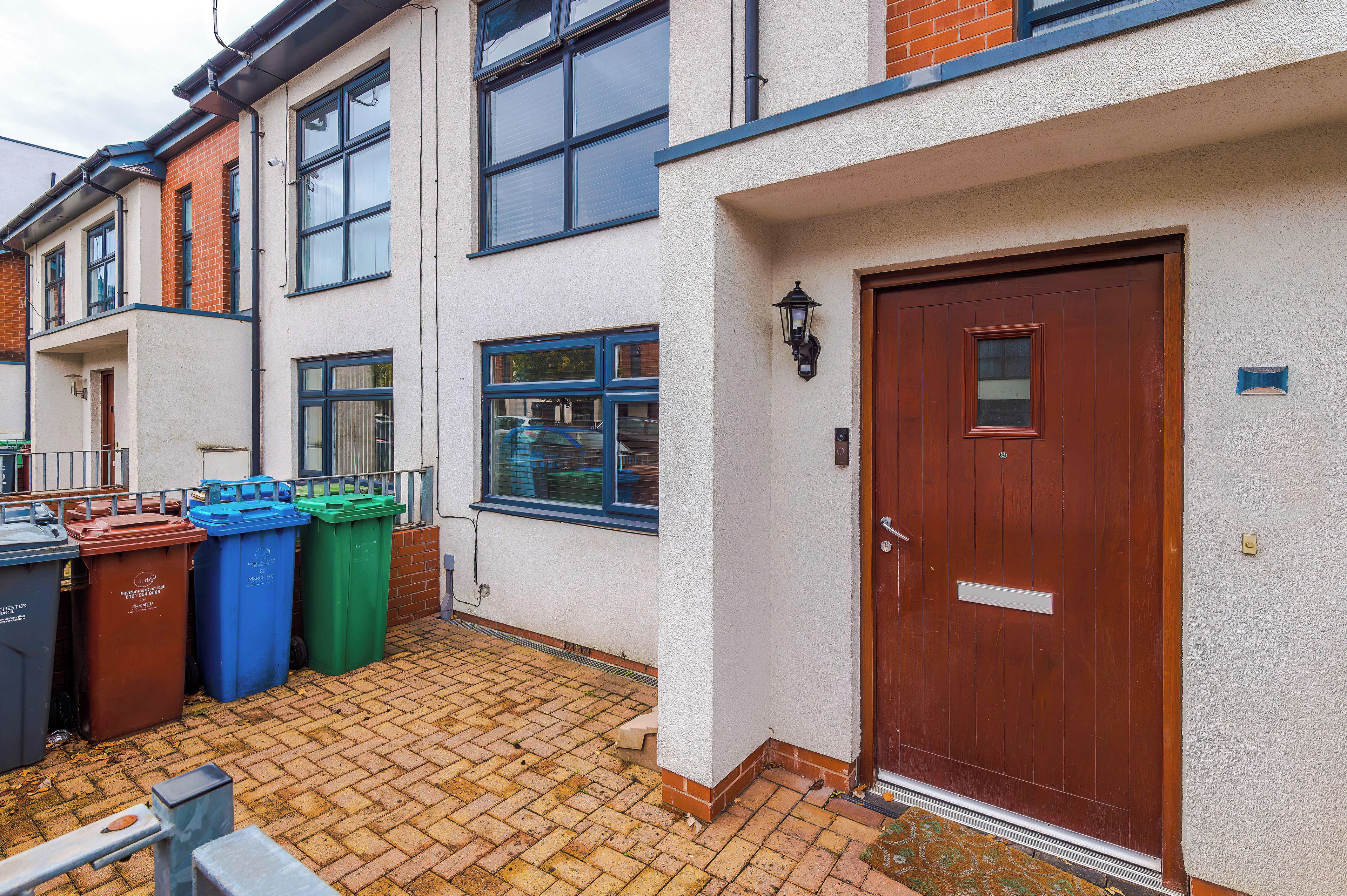 A residential building with a front door, windows, and a brick pathway.