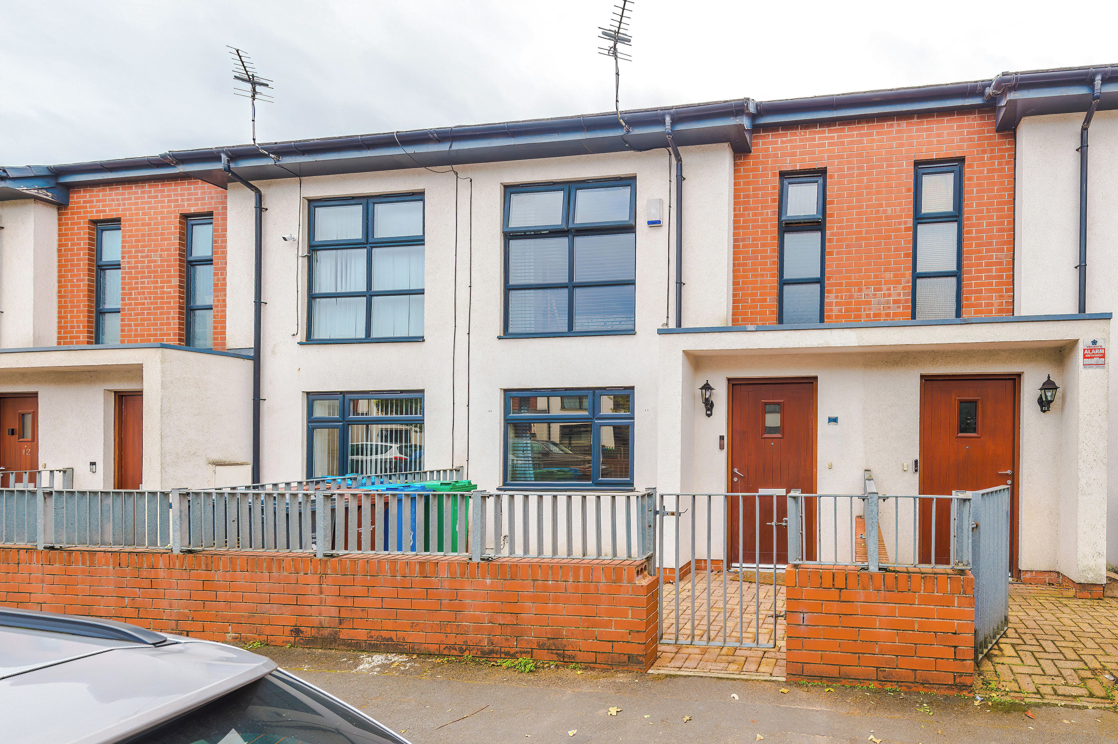 A row of terraced houses with brick facades, multiple windows, and a gated entrance.