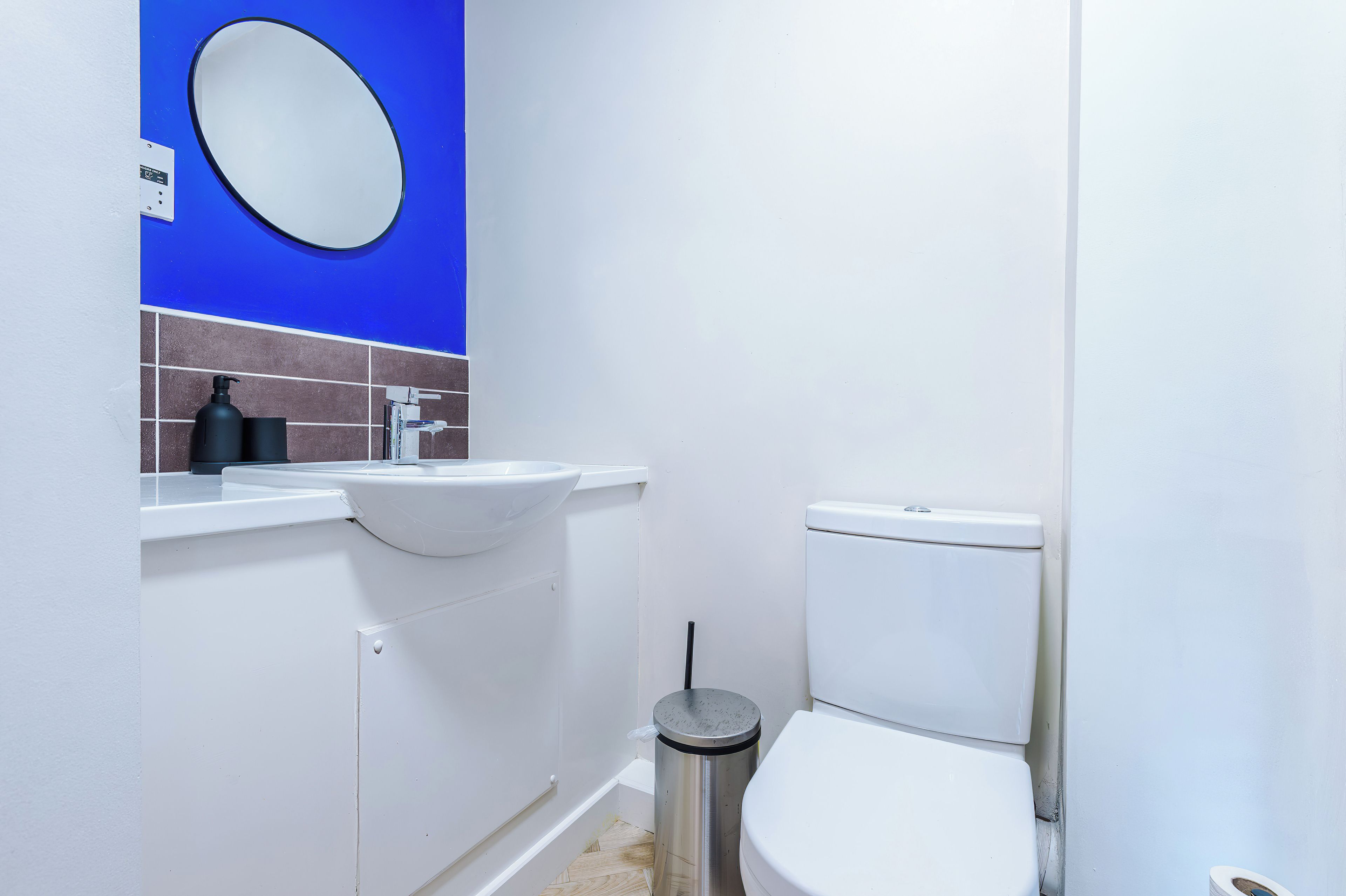 Un baño con inodoro blanco, lavamanos y espejo.