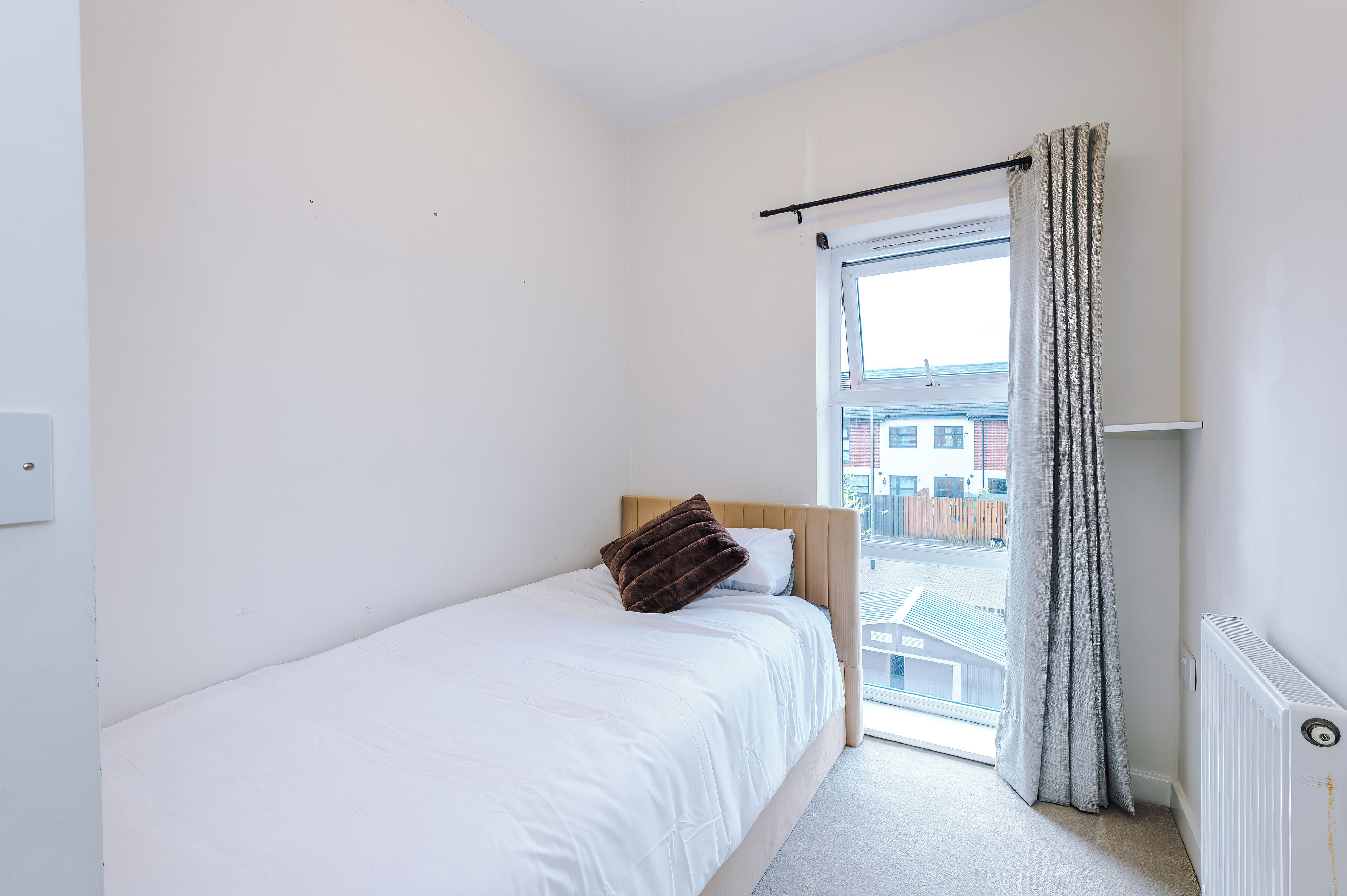 A small, single-bed room with a window and a radiator.