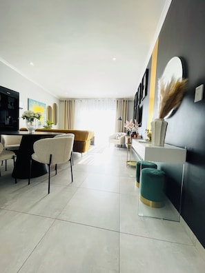 A modern living room with a dining area, a sofa, and a TV.