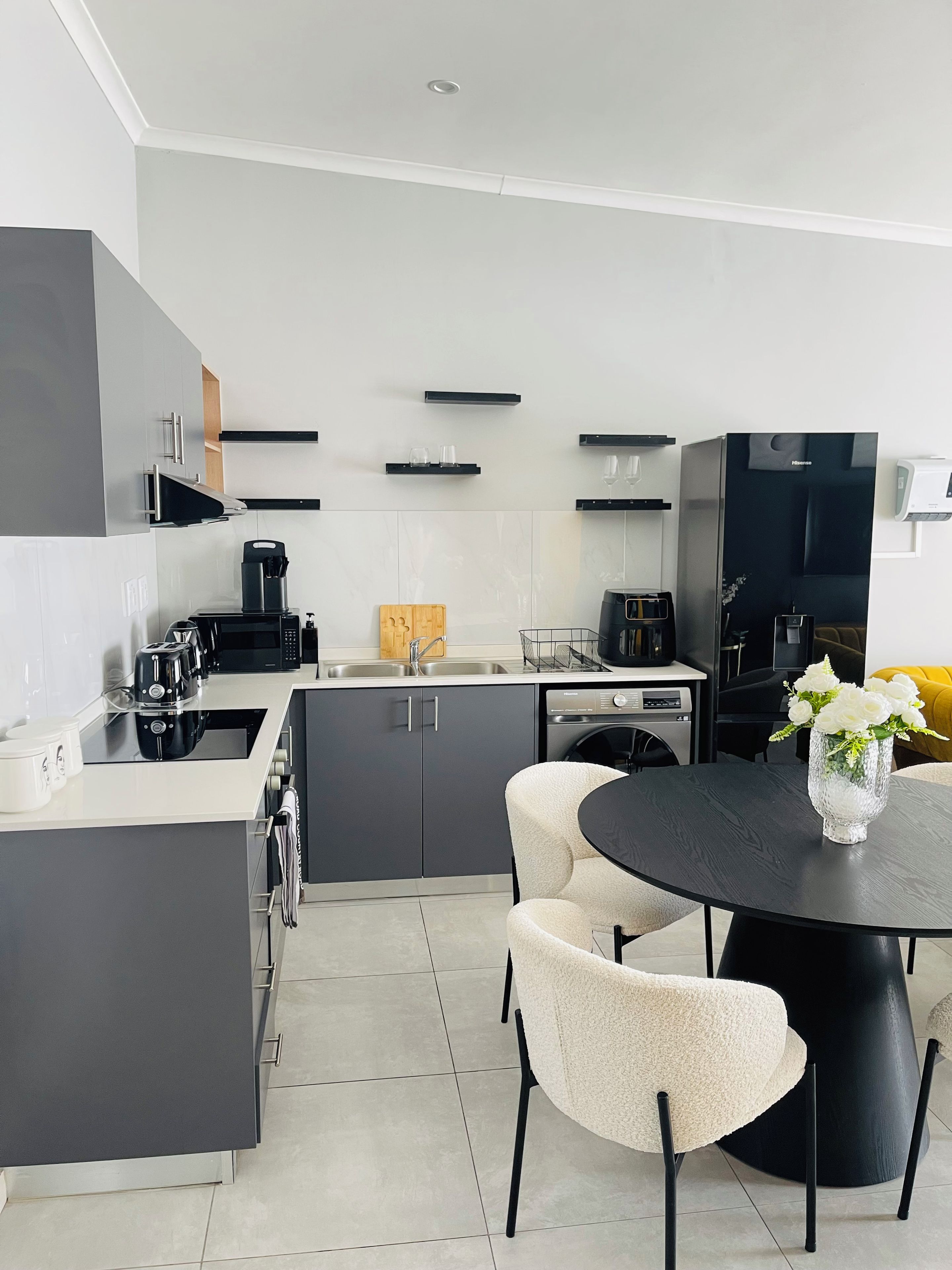 Una cocina moderna con una isla central, electrodomésticos integrados y un comedor con mesa y sillas redondas.