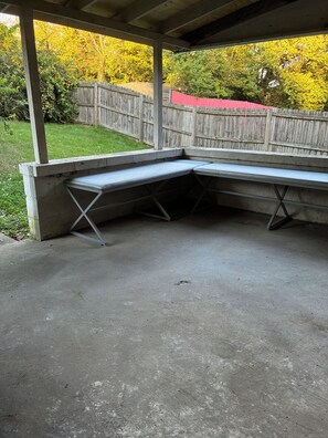 A concrete outdoor seating area with a bench and a table, surrounded by a wooden fence and a grassy yard. - Spacious 4-bedroom house in peaceful Cincinnati 5 minutes to downtown (Cincinnati)