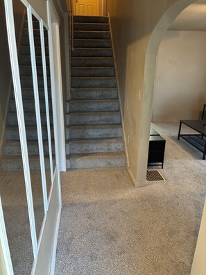 A carpeted staircase with a landing area, a black table, and a vent on the floor. - Spacious 4-bedroom house in peaceful Cincinnati 5 minutes to downtown (Cincinnati)