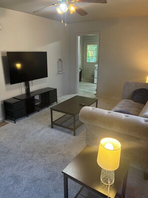 A living room with a flat-screen TV, a sofa, a coffee table, and a lamp. - Spacious 4-bedroom house in peaceful Cincinnati 5 minutes to downtown (Cincinnati)