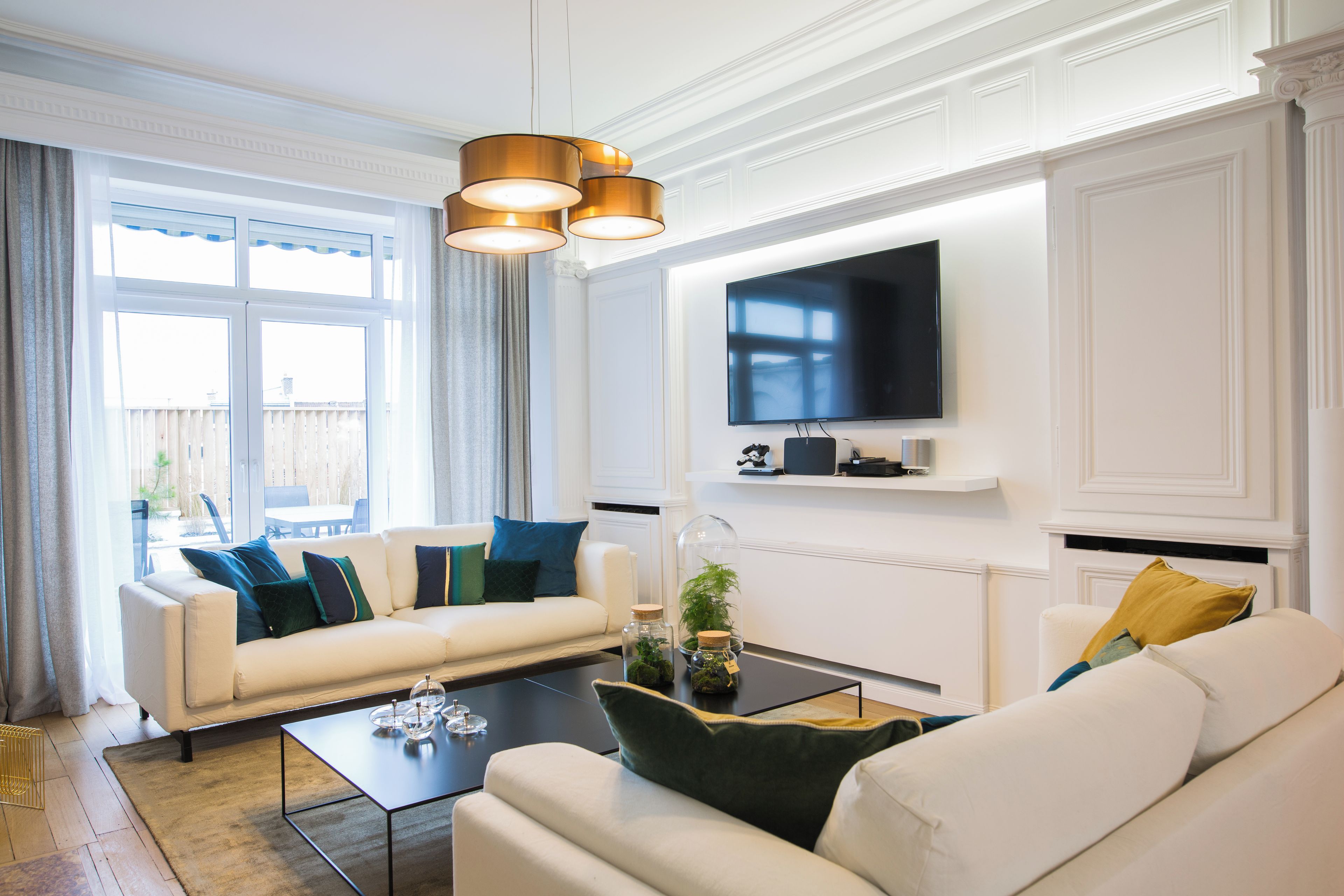 Un salon moderne avec un canapé, une table basse et un téléviseur à écran plat fixé au mur.