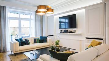 Un salon moderne avec un canapé, une table basse et un téléviseur à écran plat fixé au mur.