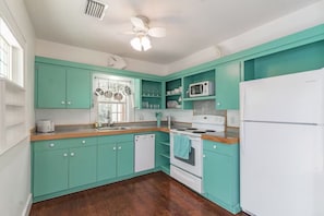 A kitchen with teal cabinets, a white refrigerator, a microwave, a stove, and a dishwasher. - Iconic Coastal retreat close to Siesta Key Beach! (Sarasota)