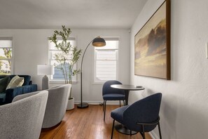 A modern living room with a sofa, two armchairs, a small table, a floor lamp, a potted plant, and a painting on the wall. - 3BR/1BA Updated South Bend Retreat Close to ND (South Bend)