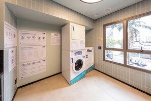 A laundry facility with instructions on the wall, a washing machine, and a dryer. - Balkon by Bhomy (São Paulo)