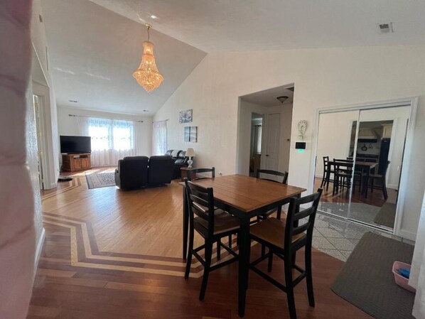 A spacious living area with a dining table and chairs, a sofa, and a television. - Charming 3-bedroom house in beautiful Harrisonburg with AC (Harrisonburg)