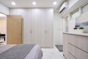 A bedroom with a bed, a wardrobe, and a vanity with a mirror.