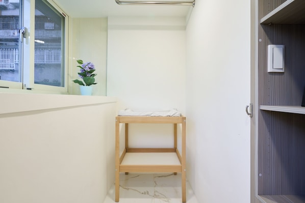 A small wooden bench in a corner of a room with a window, a potted plant, and a door.