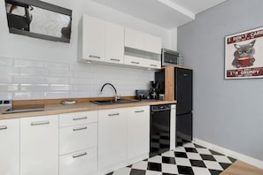 A modern kitchen with white cabinets, a black and white checkered floor, and a coffee-themed poster on the wall. - Gdynia | 31 Starowiejska | Comfortable Apartment | Centre (Gdynia)