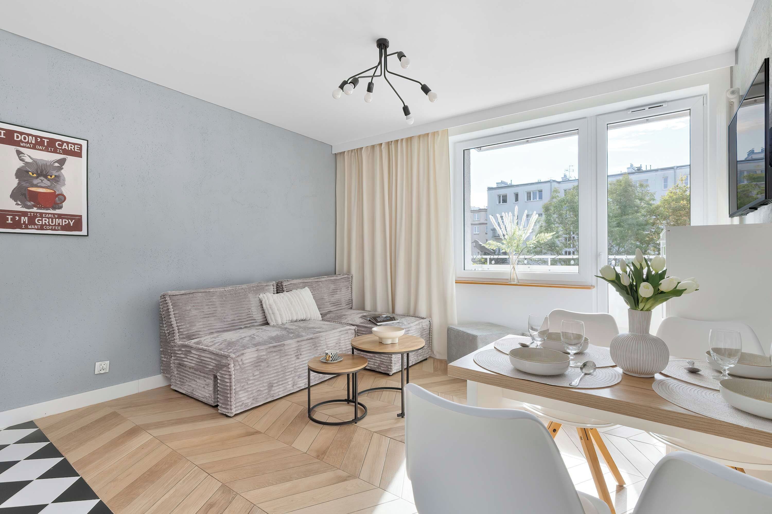Una sala de estar moderna con un sofá, una mesa de centro y un comedor con una mesa preparada para dos.