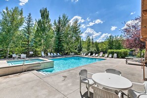 A swimming pool with lounge chairs and a table, surrounded by trees and a clear sky. - Fabulous 2-bedroom townhome in Park City on bus route (Park City)