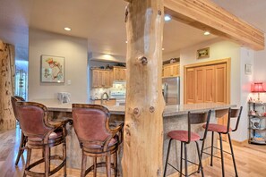 A kitchen with wooden cabinets, a central island with bar stools, and a wooden post structure. - Fabulous 2-bedroom townhome in Park City on bus route (Park City)