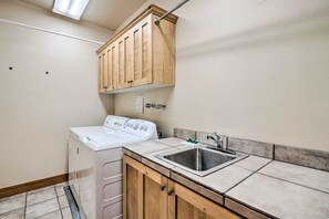 A laundry area with a washing machine, a sink, wooden cabinets, and a tiled backsplash. - Fabulous 2-bedroom townhome in Park City on bus route (Park City)