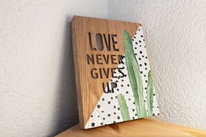 A wooden block with the text 'LOVE NEVER GIVES UP' and a cactus illustration. - A studio apartment just a 5-minute walk from the cable cars (Crans-Montana)