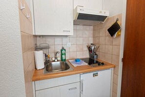 A compact kitchenette with a sink, stove, and storage cabinets. - A studio apartment just a 5-minute walk from the cable cars (Crans-Montana)